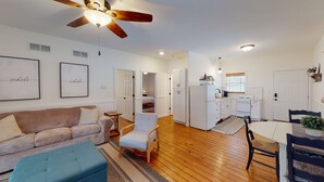 A spacious living area with a brown sofa, a blue ottoman, and a wooden ceiling fan. - Beach Access to Ozark, Visit the Cottage on Valley Road! (Osage Beach)