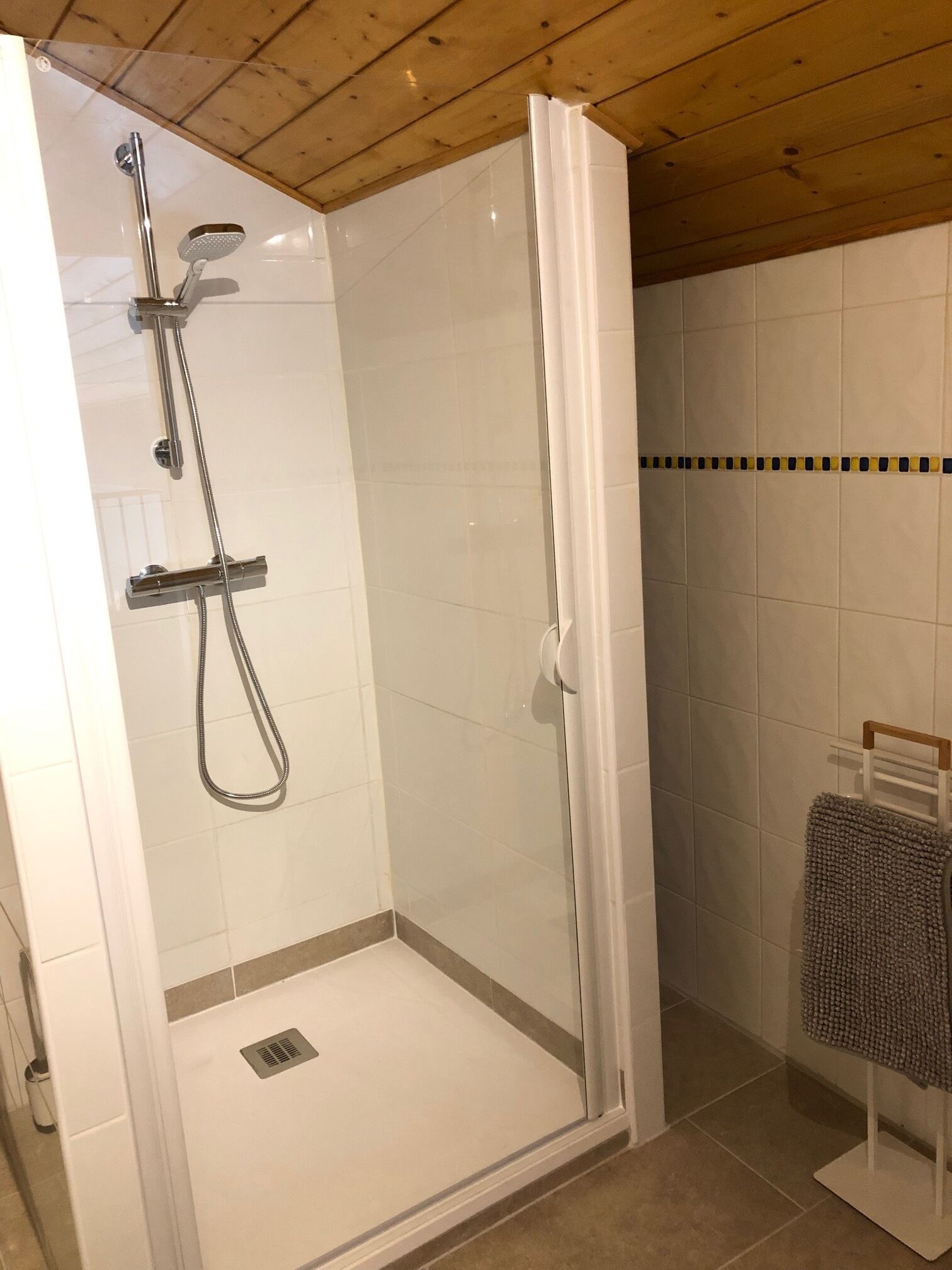 A glass-enclosed shower with a handheld showerhead and a wall-mounted faucet.