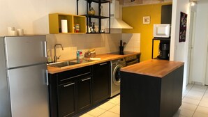 A modern kitchen with a stainless steel refrigerator, a washing machine, and a coffee maker. - Villa Ferry (Andernos-les-Bains)