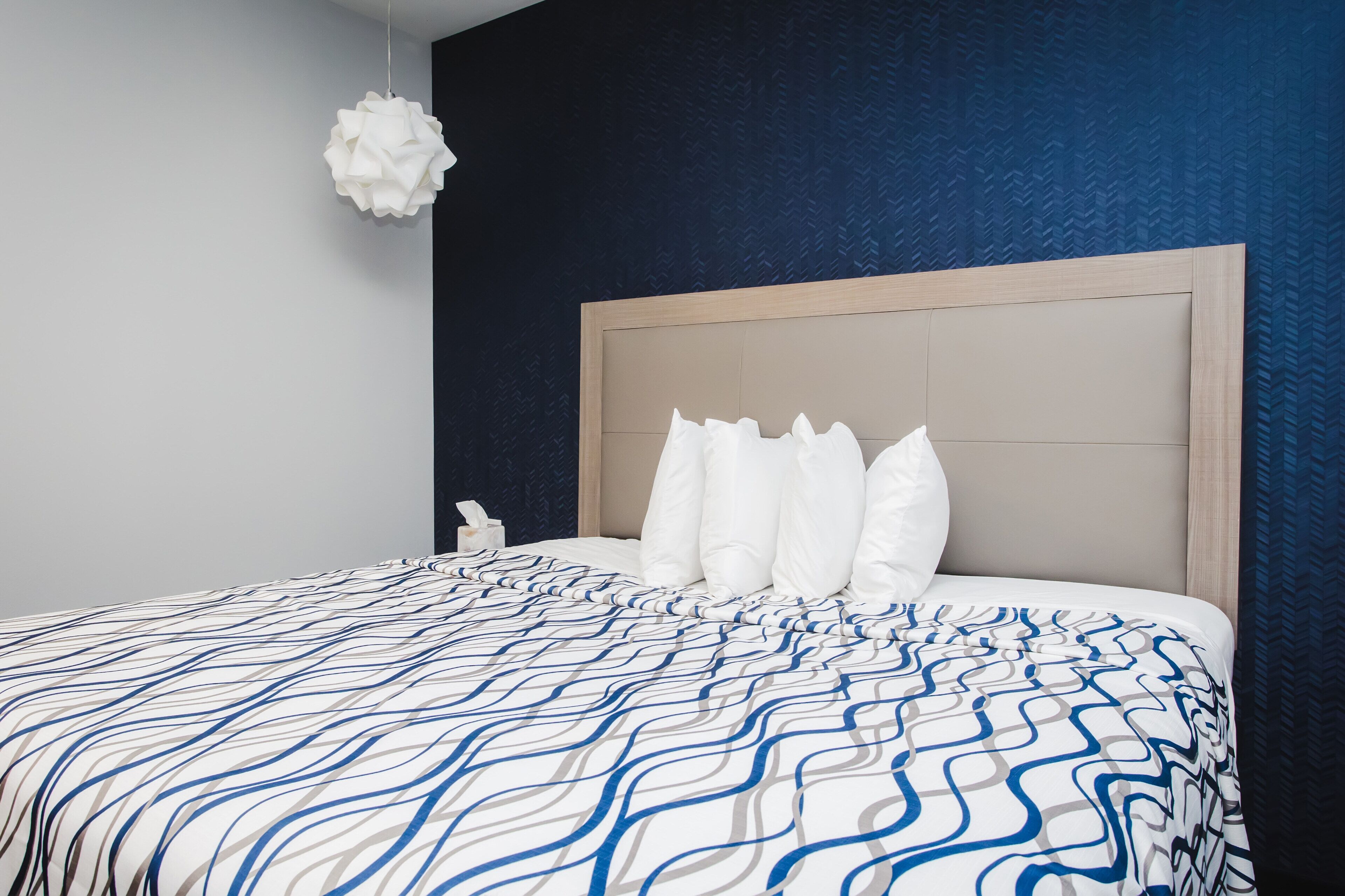 Un dormitorio con una cama grande, cabecera de madera y pared blanca.