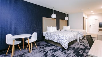 A hotel room with a bed, a desk, two chairs, and a small table.