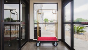 A view through a large glass door into a room with a pull-up bar and a cart. - Palace Inn Blue Houston East Beltway 8 (Houston)