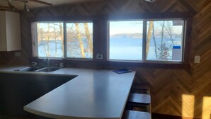 A kitchen with a large window, wooden herringbone ceiling, and a bar area.