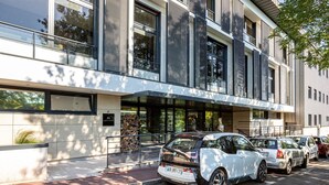 Un bâtiment moderne doté de grandes fenêtres et d’un parking où sont stationnées plusieurs voitures.