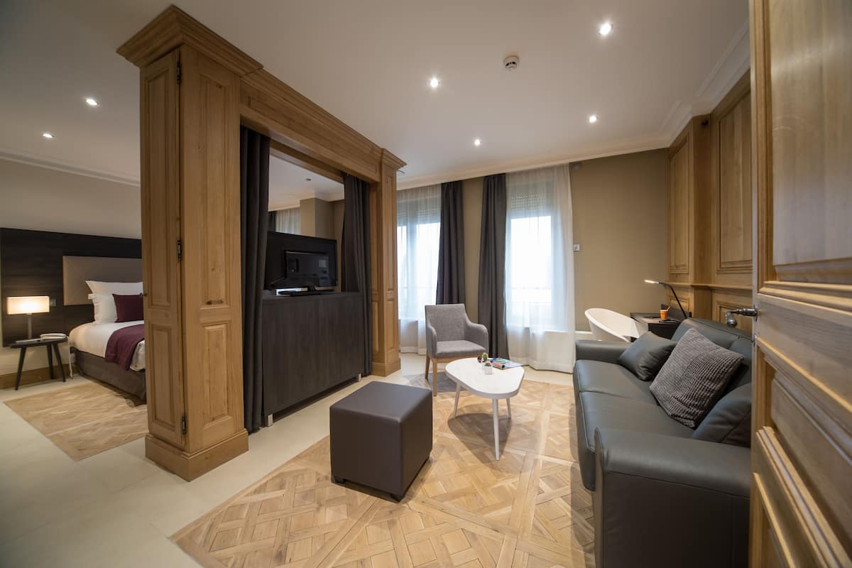 Ein modernes Hotelzimmer mit Bett, einer Couch, einem kleinen Tisch und einem Fernseher.