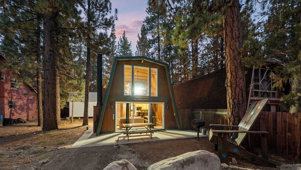 A wooden cabin with a large sliding glass door, surrounded by trees.