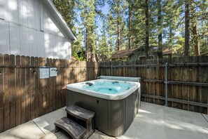 Un jacuzzi en un patio trasero con valla de madera y terraza de madera.