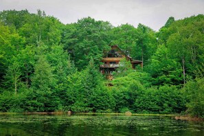 A cabin surrounded by dense forest and a lake.