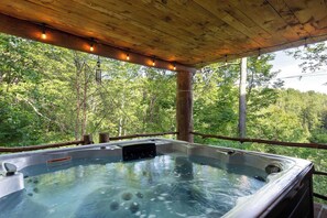 Un jacuzzi con cubierta de madera y vista al bosque.