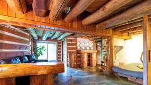 L’intérieur d’une cabane en rondins, avec un banc en bois, un canapé, un escalier et un lit.