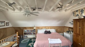 A bedroom with a bed, wooden headboard, a bookshelf, a desk, and a wardrobe.