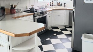 A kitchen with white cabinets, a black and white checkered floor, a stainless steel refrigerator, and a window with a view of the outdoors. - Downtown Ketchikan /million Dollar View (Ketchikan)