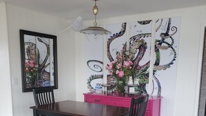A dining area with a wooden table, chairs, and a bench. There is a mirror on the wall, a ceiling fan, and decorative wall art. - Downtown Ketchikan /million Dollar View (Ketchikan)