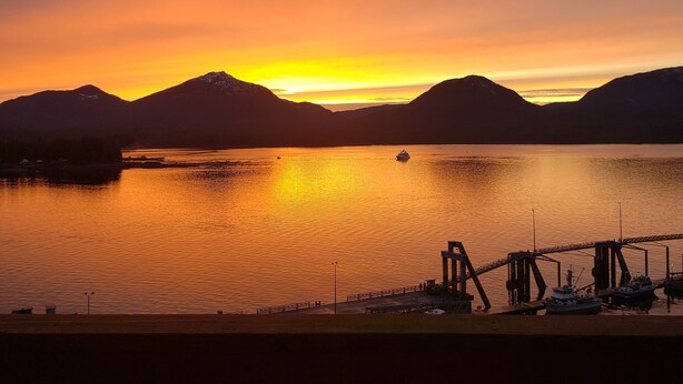 A sunset over a calm lake with mountains in the background and a dock with boats. - Downtown Ketchikan /million Dollar View (Ketchikan)