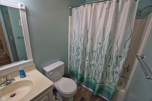 A bathroom with a toilet, sink, and shower curtain.