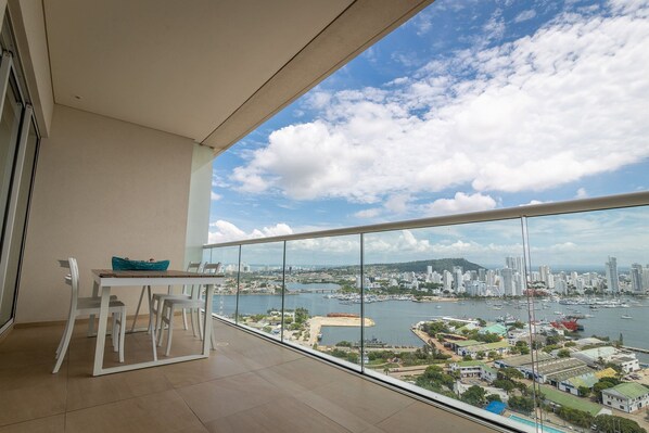 A balcony with a table and chairs, overlooking a marina with boats and a cityscape. - Spectacular apartment in H2, 20th floor! (Cartagena)