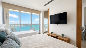 A hotel room with a large balcony, a TV, and a view of the city.