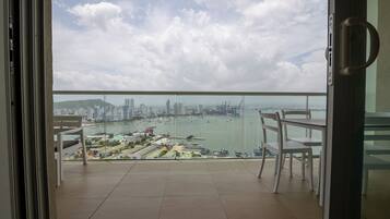 A balcony with a view of a cityscape, including a body of water and buildings.