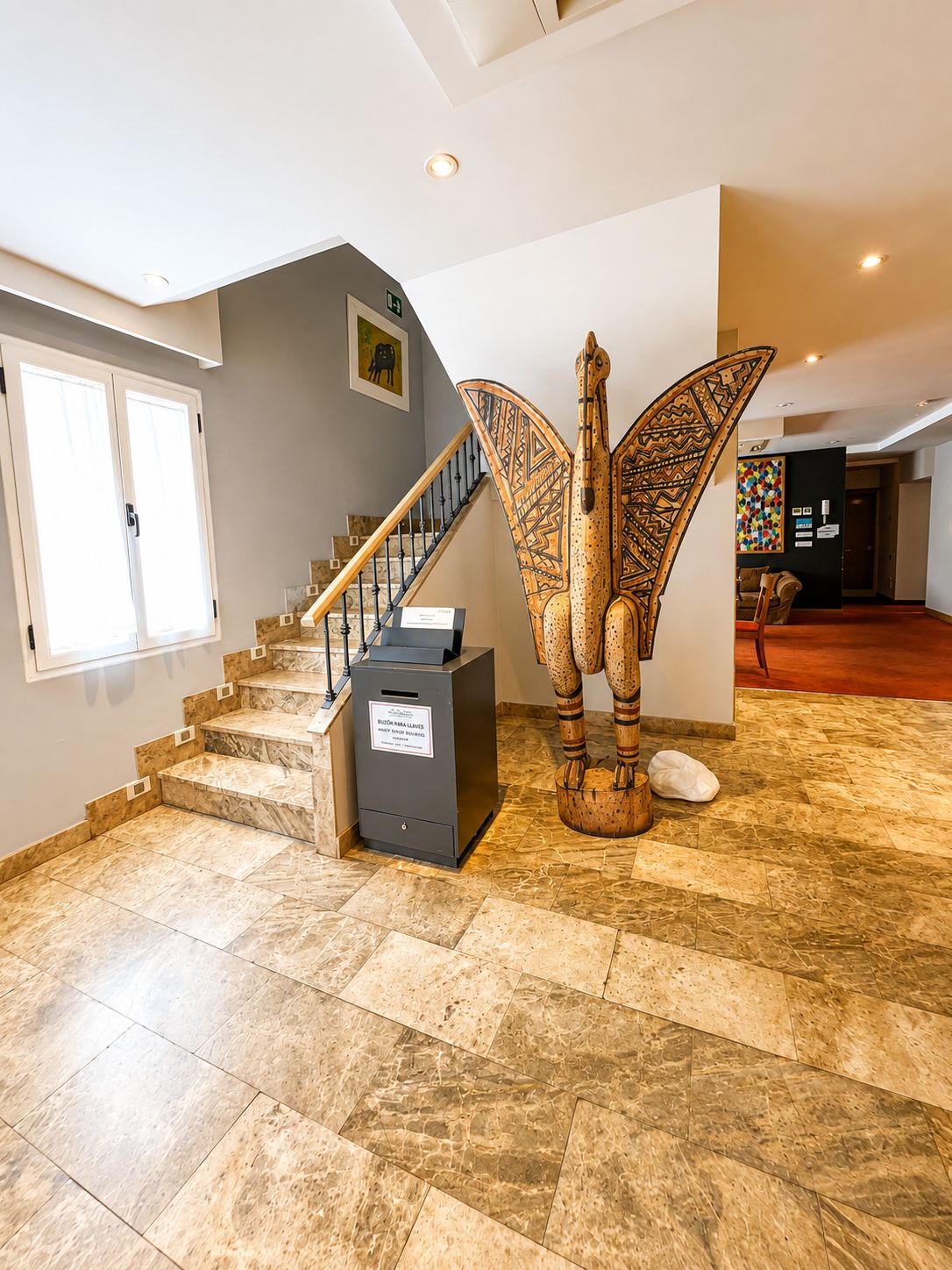Un intérieur spacieux avec un sol en marbre, un escalier et une grande sculpture décorative.