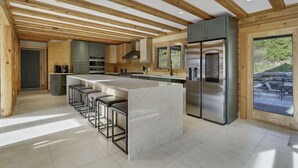 A modern kitchen with a central island, bar stools, stainless steel appliances, and wooden beams. - Indoor Pool, Giant Game Room Party Lodge, Entire Estate Rental  (Hancock)