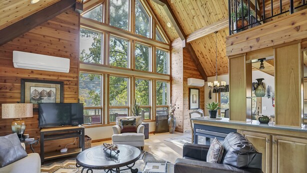 A spacious living area with a large TV, comfortable seating, and a kitchen area with a dining table and bar. - Indoor Pool, Giant Game Room Party Lodge, Entire Estate Rental  (Hancock)