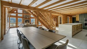 A spacious wooden cabin with a large dining table, a kitchen area, and a staircase leading to a loft. - Indoor Pool, Giant Game Room Party Lodge, Entire Estate Rental  (Hancock)
