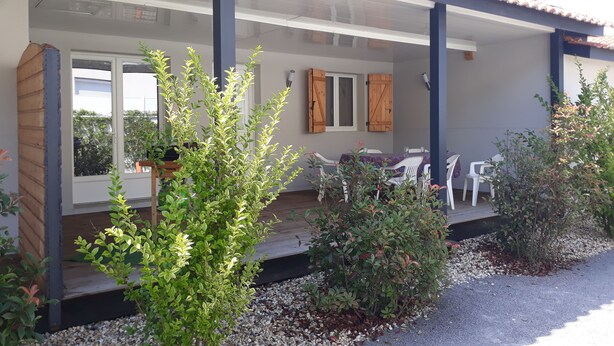 A covered outdoor seating area with a table and chairs, surrounded by plants and a gravel path. - Nice Appart T3 duplex 4pers-Clim- 5mn from the Port Ostréicole de la Teste de Buch (La Teste-de-Buch)
