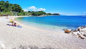 A beach with pebbles, a few people, and a blue structure.