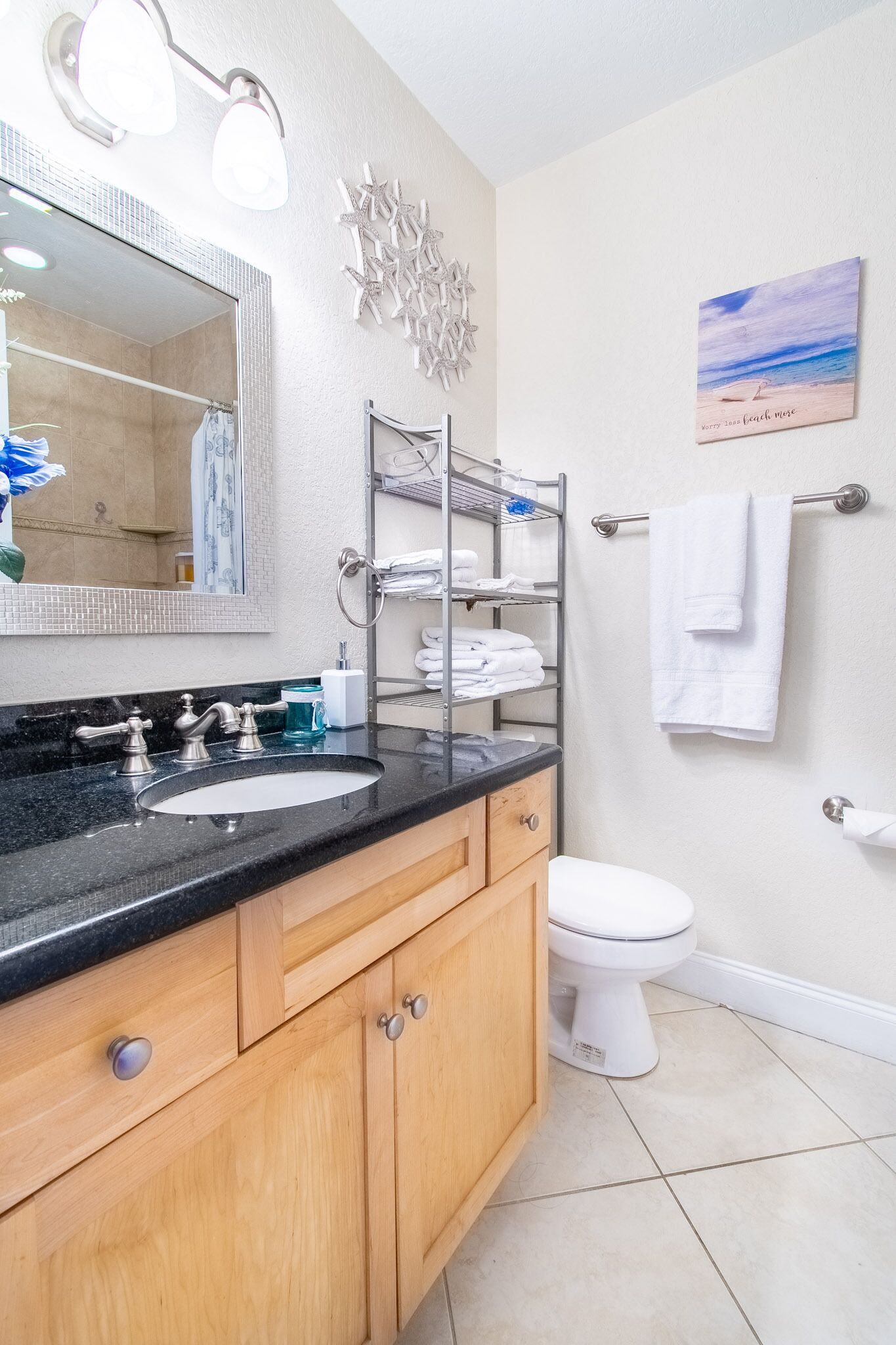 A bathroom with a sink, mirror, towel rack, and a shelf with towels.