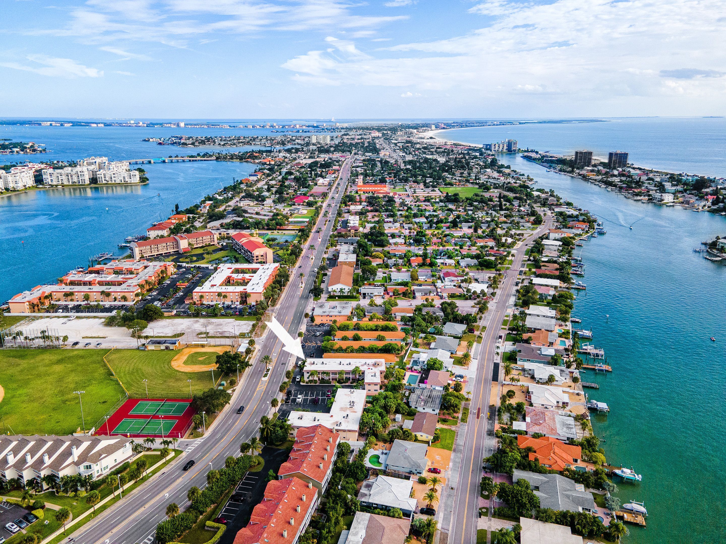 An aerial view of a coastal city with a marina, residential areas, and a sports complex.