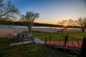 Un parc au bord de la rivière, doté d’une terrasse en bois, de tables de pique-nique et offrant une vue sur le coucher de soleil sur l’eau.