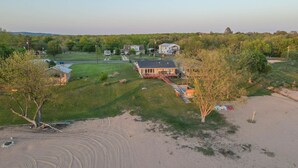 Une grande maison avec un vaste jardin, une piscine et une plage de sable.
