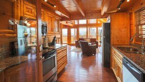 A spacious kitchen with wooden cabinets, granite countertops, and a large island. - Secluded Cabin w/Mtn. Views, 3 Decks & Theater (Sevierville)