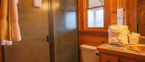 Une salle de bain avec un meuble-lavabo en bois, des toilettes et un espace douche.