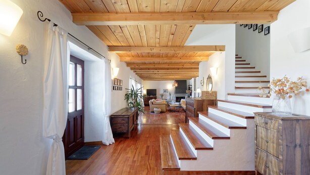 Amplia sala de estar con piso de madera, una escalera y una zona de estar acogedora.
