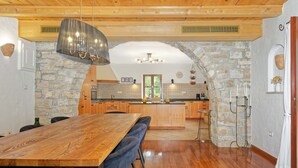 Una cocina amplia con un arco de piedra, techo de madera y una gran mesa de comedor de madera.