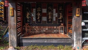 En traditionel japansk helligdom med trækonstruktion, et tag med fliser og en lille platform med en lygte.