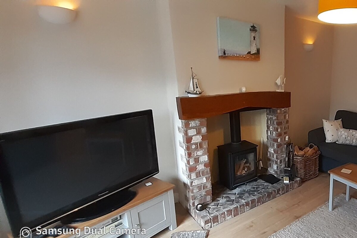 A living room with a TV, fireplace, sofa, and artwork on the walls.