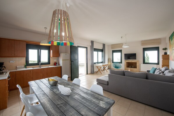 Relax in this inviting living space with a central dining table, comfortable sofa, and kitchen amenities.