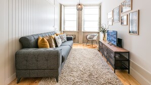 A modern living room with a grey sofa, a wooden coffee table, and a TV on a stand. - GuestReady - Oporto Temptation Apartment (Porto)