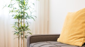 Un canapé avec un coussin à texture et une plante en pot placée à côté.
