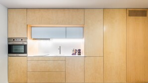 Une cuisine moderne avec des meubles en bois, un four encastré et un évier en acier inoxydable.