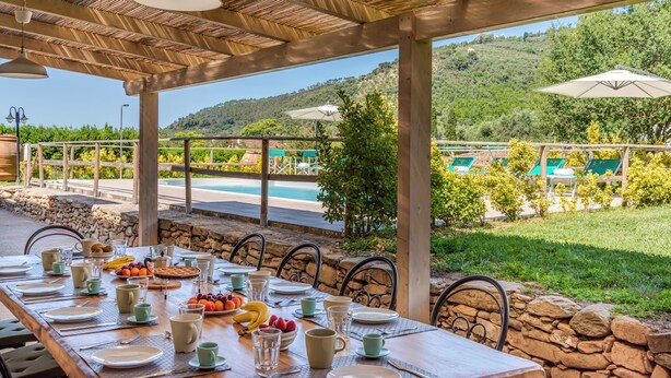 A dining area with a table set for a meal, overlooking a pool and lush greenery. - PRIVATE POOL - AGRITURISMO FATTORIA LA PIEVE - VILLA NERINO 8 km from Pisa  (Calci)