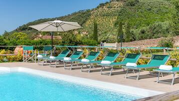 A poolside area with lounge chairs and a large umbrella.