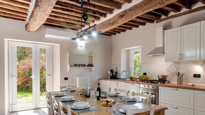 A modern kitchen with white cabinets, a wooden dining table set for six, and a large window overlooking a garden. - PRIVATE POOL - AGRITURISMO FATTORIA LA PIEVE - VILLA NERINO 8 km from Pisa  (Calci)