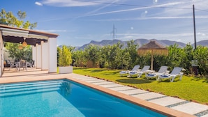 Ein Schwimmbecken mit Liegestühlen, einer Pergola und Blick auf Berge.