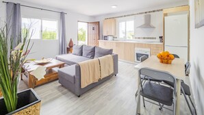 Ein modernes Wohnzimmer mit grauem Sofa, einem kleinen Tisch und einem Essbereich mit Tisch und Stühlen.