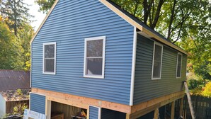 A two-story house with a blue exterior and a wooden deck. - Track and seasonal rental (Saratoga Springs)