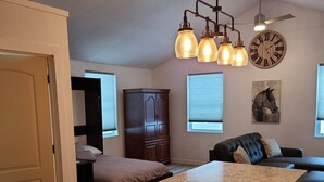 A kitchen with a granite island, dark wooden cabinets, a ceiling fan, and pendant lights. - Track and seasonal rental (Saratoga Springs)