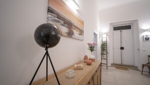 A hallway with a wooden console table, a globe on a tripod, a painting, a vase with flowers, and a door with a 'Free Wi-Fi' sign. - Dimora Fantasia Charme B&B (Bari)